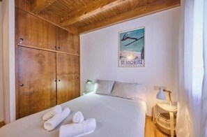 Une chambre d’hôtel avec un lit, une armoire en bois, un tableau encadré au mur et une table de chevet avec une lampe.