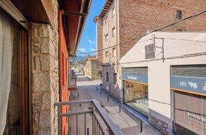 Une rue étroite bordée d’immeubles en pierre, avec un balcon et un magasin dont l’enseigne est visible.