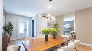Un comedor con una mesa de madera, seis sillas y dos plantas en macetas.