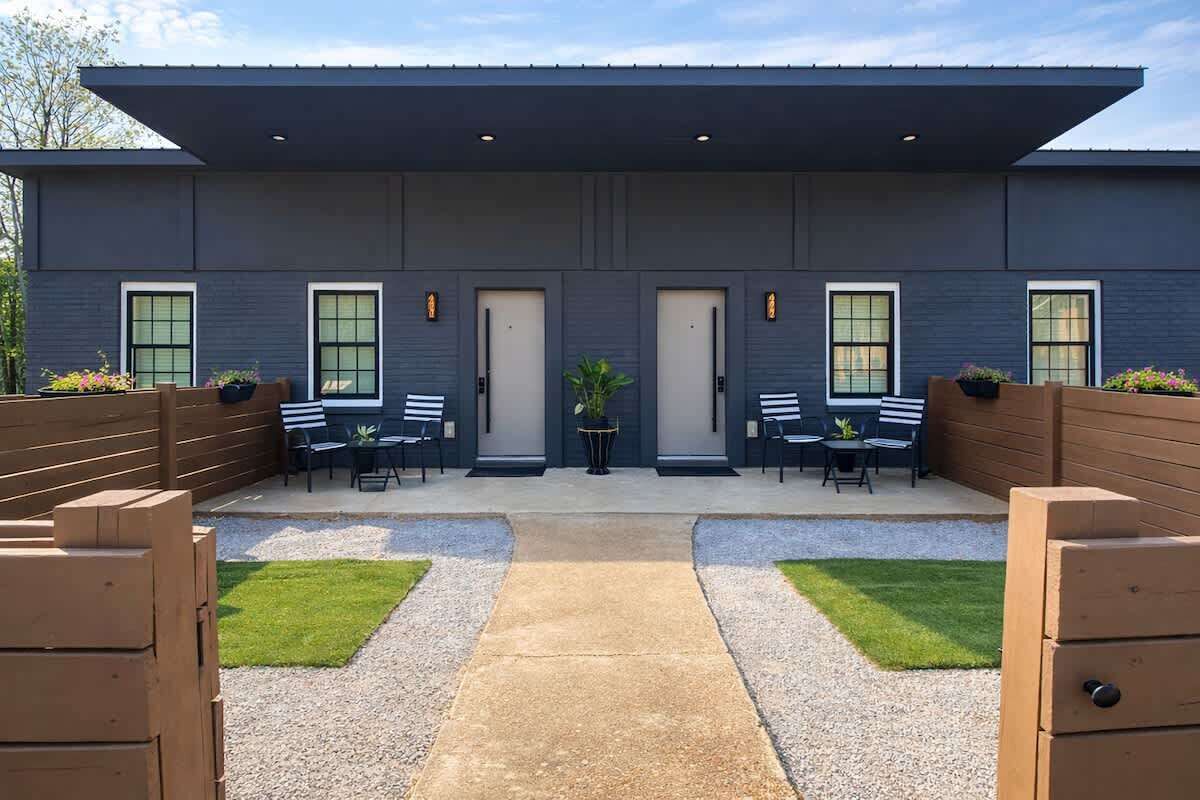 A modern building with a flat roof, large windows, and a covered outdoor seating area with tables and chairs.