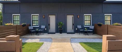 A modern building with a flat roof, large windows, and a covered outdoor seating area with tables and chairs.
