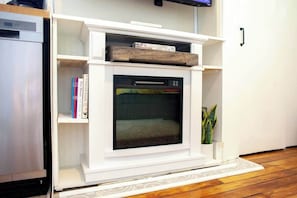 A white fireplace with a glass door, surrounded by white shelves and a small plant. - Civil Rights Trail Townhome - Near Historic Sites (Montgomery)