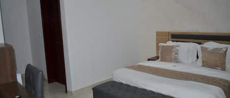 A bedroom with a bed, bedside tables, a desk, and a chair.