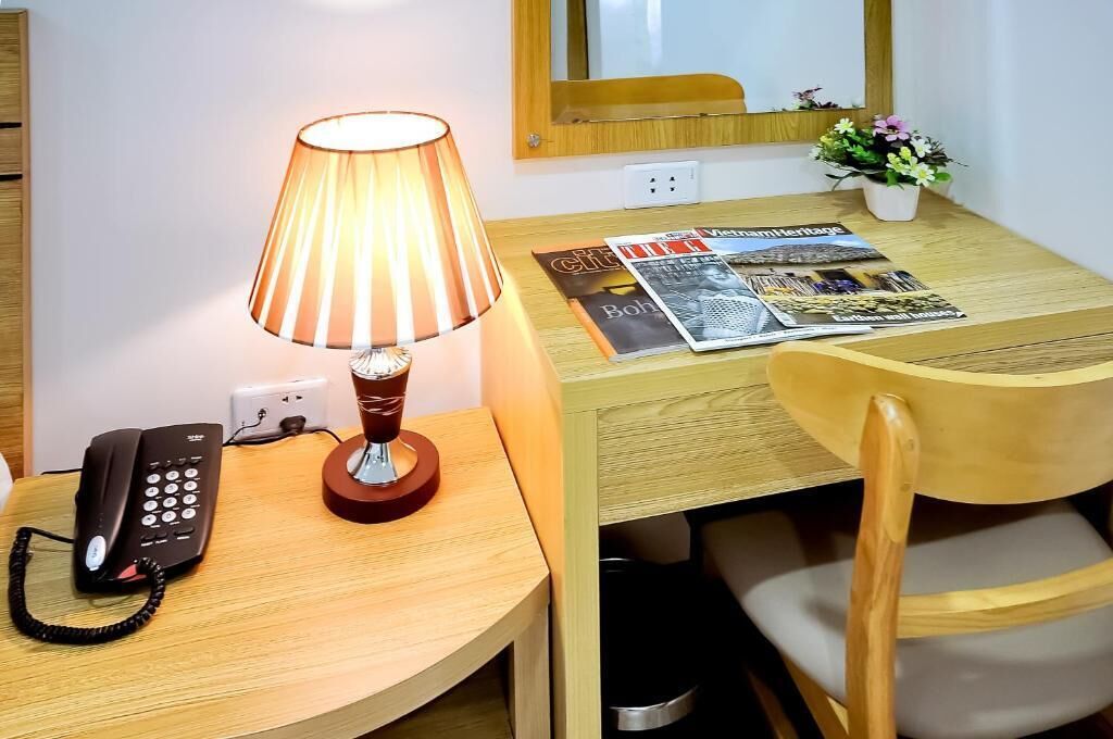 Un bureau en bois avec une lampe, un téléphone et un magazine.
