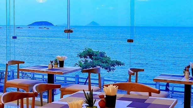 A restaurant with tables and chairs facing a body of water.