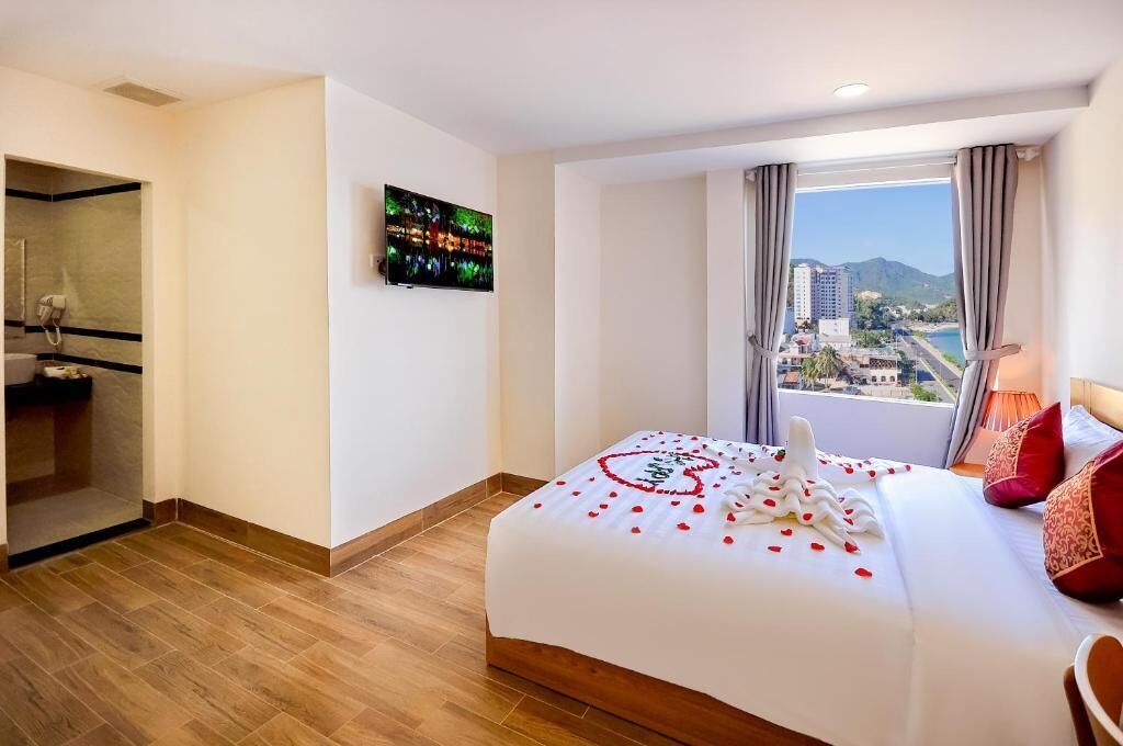 Habitación de hotel con cama, televisión, baño y vistas a la ciudad.