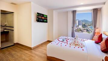 Habitación de hotel con cama, televisión, baño y vistas a la ciudad.