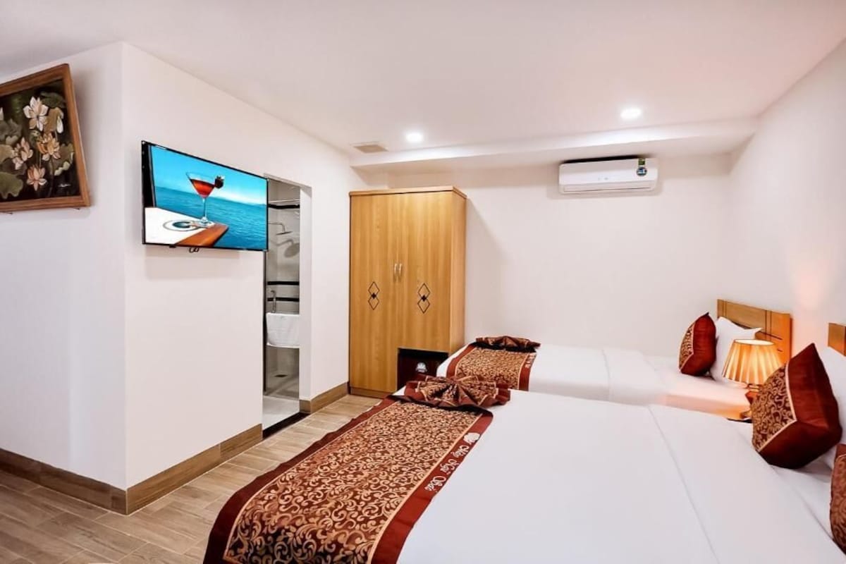 Quarto de hotel com uma cama, televisão, guarda-roupa e ar condicionado.