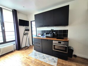 A compact kitchen with a built-in oven, a microwave, and a sink. - Studio Cosy Mer & Bus St-Malo (Dinard)