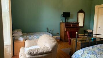 A bedroom with a bed, a chair, a dresser, a television, and a mirror.