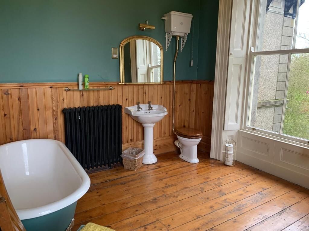 A bathroom with a bathtub, sink, toilet, and a window with a view.