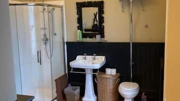 A bathroom with a shower, sink, toilet, and a mirror.