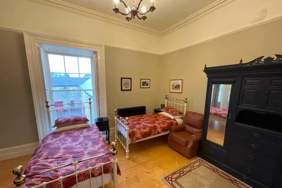 A bedroom with a bed, a chair, a dresser, and a window.