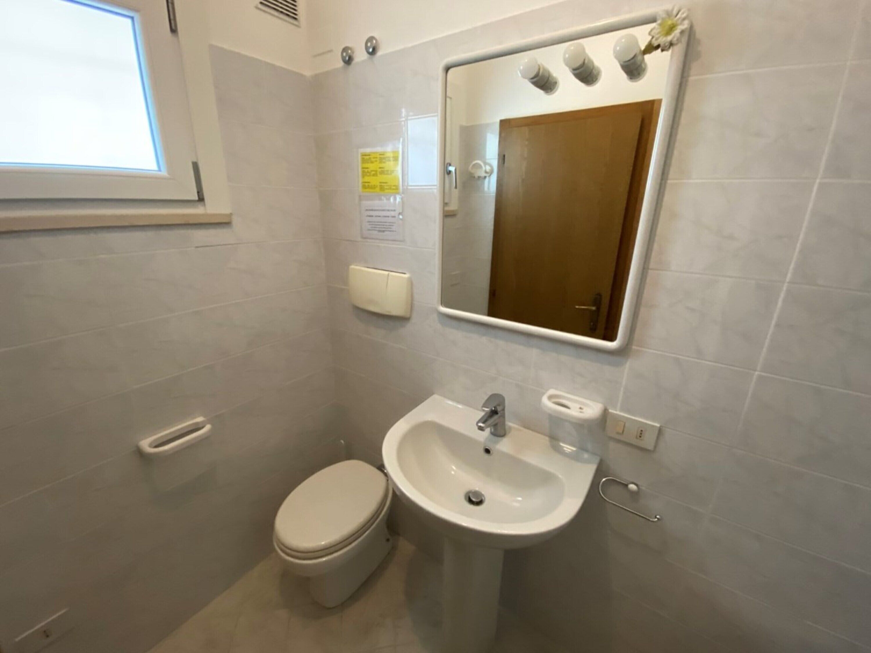 Une petite salle de bain avec des toilettes, un lavabo et un miroir.