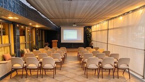 A conference room with chairs arranged in rows, a projector screen, and a presentation. - hotel mamatila (Lima)