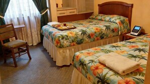 A hotel room with two beds, a desk, a chair, a small table with a tray of breakfast, and a bedside phone. - hotel mamatila (Lima)