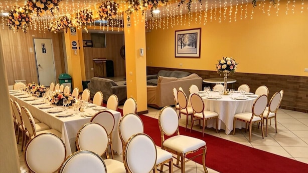 A banquet hall with round tables, white chairs, and floral centerpieces. - hotel mamatila (Lima)