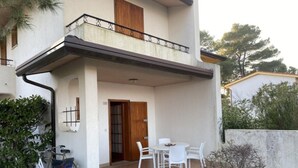 Un edificio con un balcone, una porta e un patio con sedie e un tavolo.