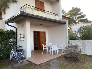 Ein Gebäude mit Balkon, einer Tür und einer Terrasse mit Stühlen und Tisch.