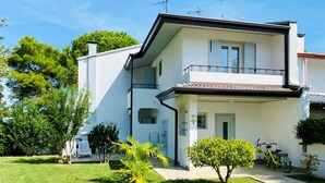 Un edificio a due piani con un balcone, una bicicletta parcheggiata fuori e un prato ben curato.
