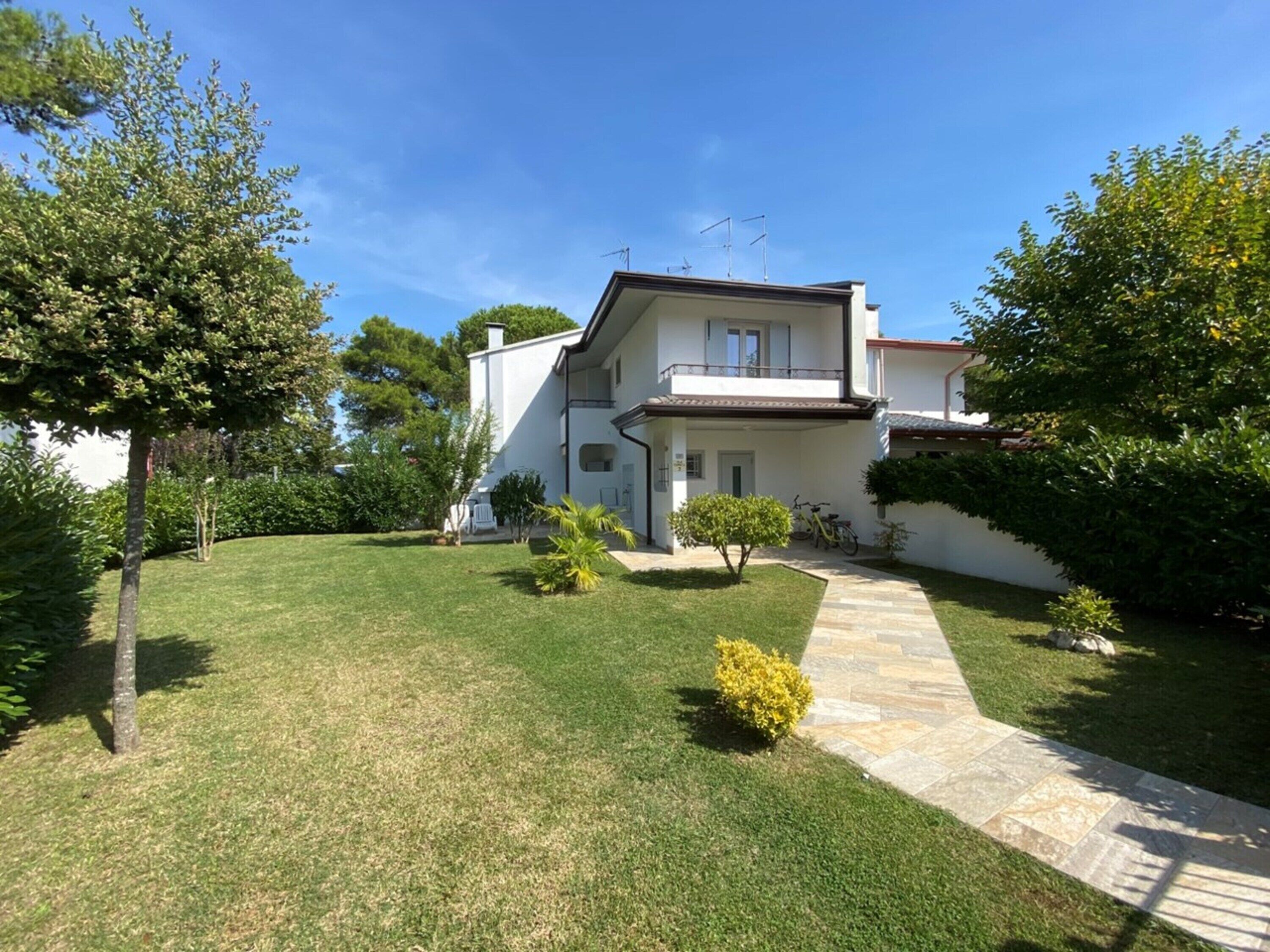 A two-story house with a paved driveway, a small garden, and a bicycle parked outside.