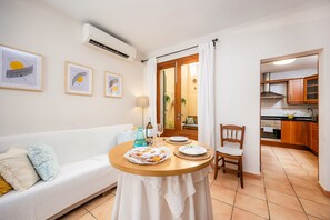 A dining area with a table, chairs, a sofa, and a kitchen in the background. - Holiday Home 'Es Port' with Wi-Fi (Porto Cristo)