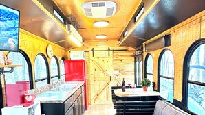 Interior de un vagón de tren con cocina, asientos y ventanas amplias.
