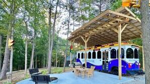 Un espacio al aire libre cubierto con bancos y sillas, un autobús techado y un semáforo.