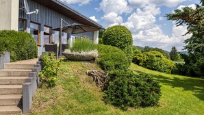 Una casa moderna con un porche cubierto, una escalera de piedra y setos bien cuidados.