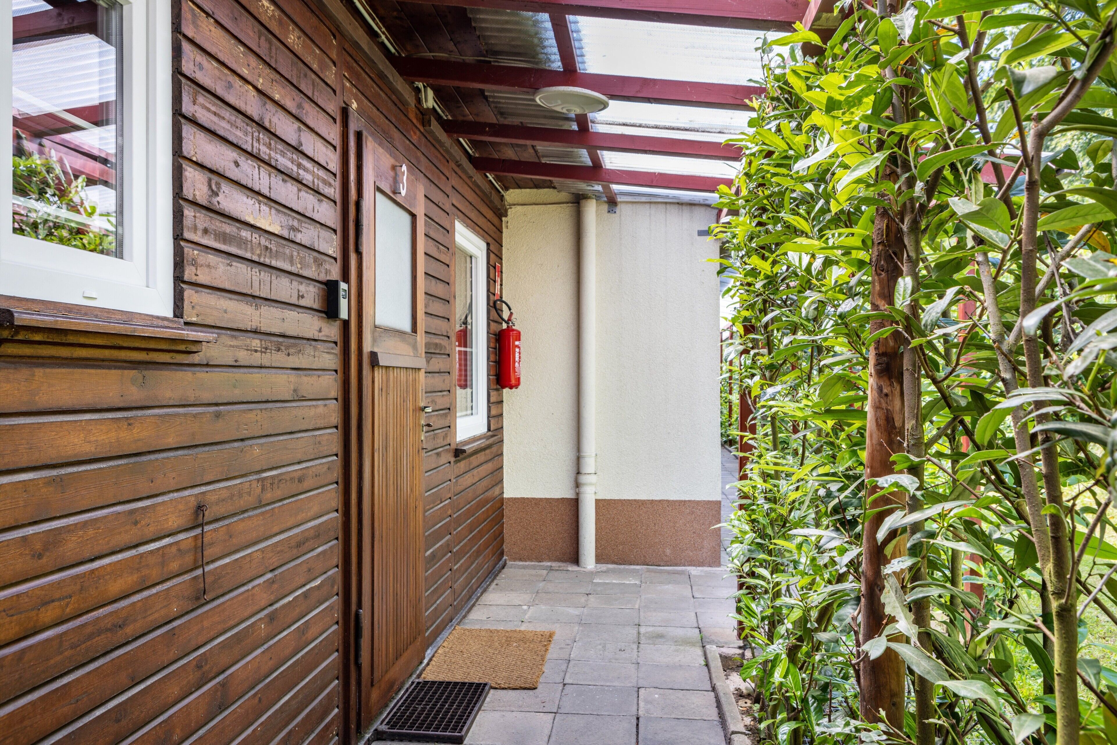 A wooden building with a window, a door, and a fire extinguisher mounted on the wall.
