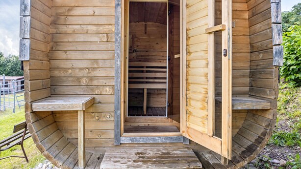 A wooden log cabin with a central door, a bench outside, and a small porch. - Studio Apartment with Mountain View, Private Terrace and Wi-Fi (Ruhla)