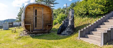 A wooden cabin with a door, a chair, and a staircase leading up to it.
