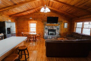 Ein Holzblockhaus mit Küche, Essbereich, Kamin und Wohnzimmer.
