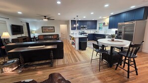 Una cocina moderna con armarios oscuros, una isla central y un comedor con una mesa redonda y sillas.