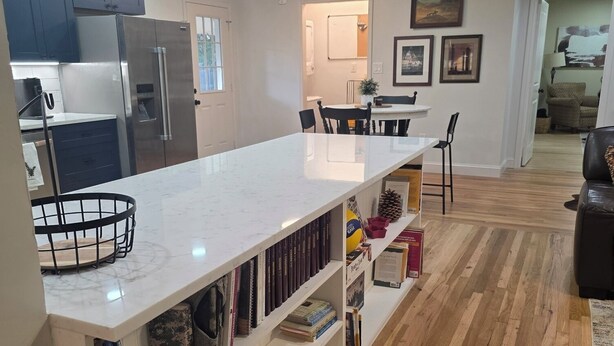Una cocina moderna con encimera de mármol, suelo de madera e iluminación colgante.