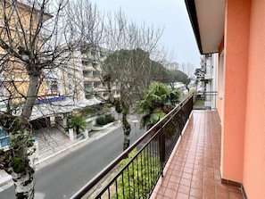 Ein Balkon mit Blick auf eine Straße, Bäume und Gebäude.