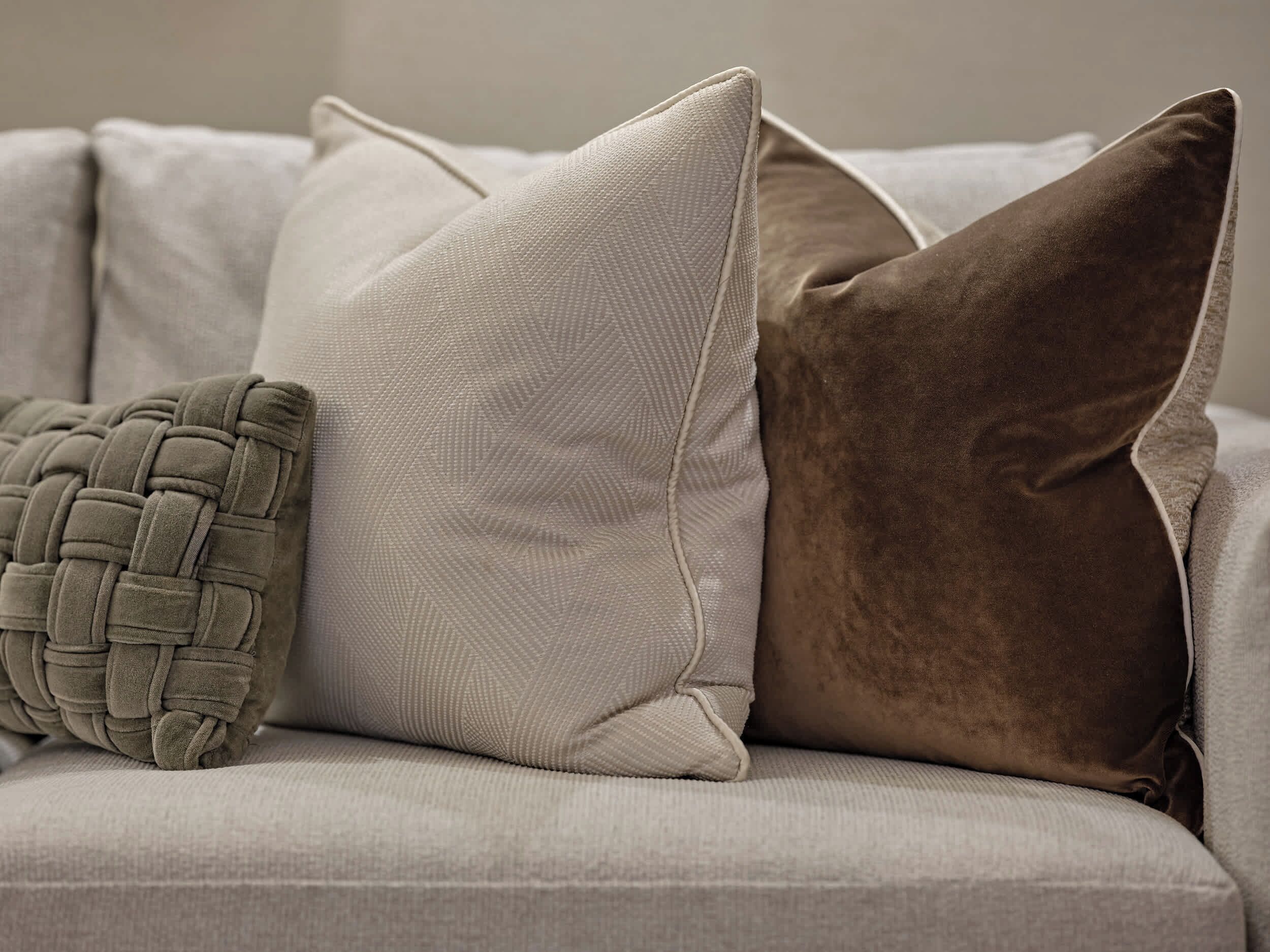 Un sofá con tres almohadones de diferentes texturas y diseños.