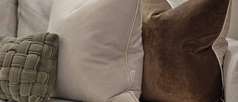 Un sofá con tres almohadones de diferentes texturas y diseños.