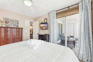Ein Hotelzimmer mit Bett, Holzkommode, Fernseher und Blick ins Freie.