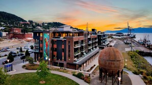A modern building with a mural, a large water tank, and a marina in the background. - Bellingham Waterfront Penthouse • Wraparound Balcony, Downtown & Near WWU (Bellingham)