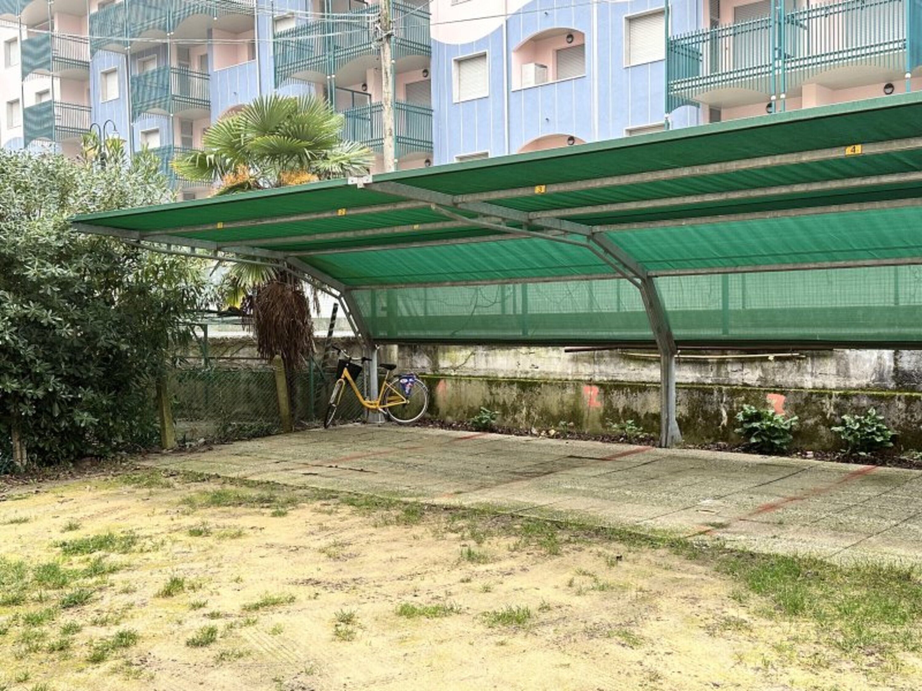 Un espace extérieur abrité avec un vélo, un sol en béton et un bâtiment doté de balcons en arrière-plan.