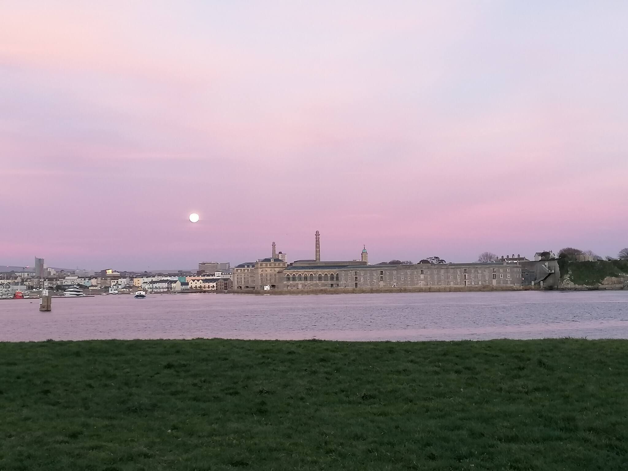 A waterfront view with a large building, a tower, and boats.