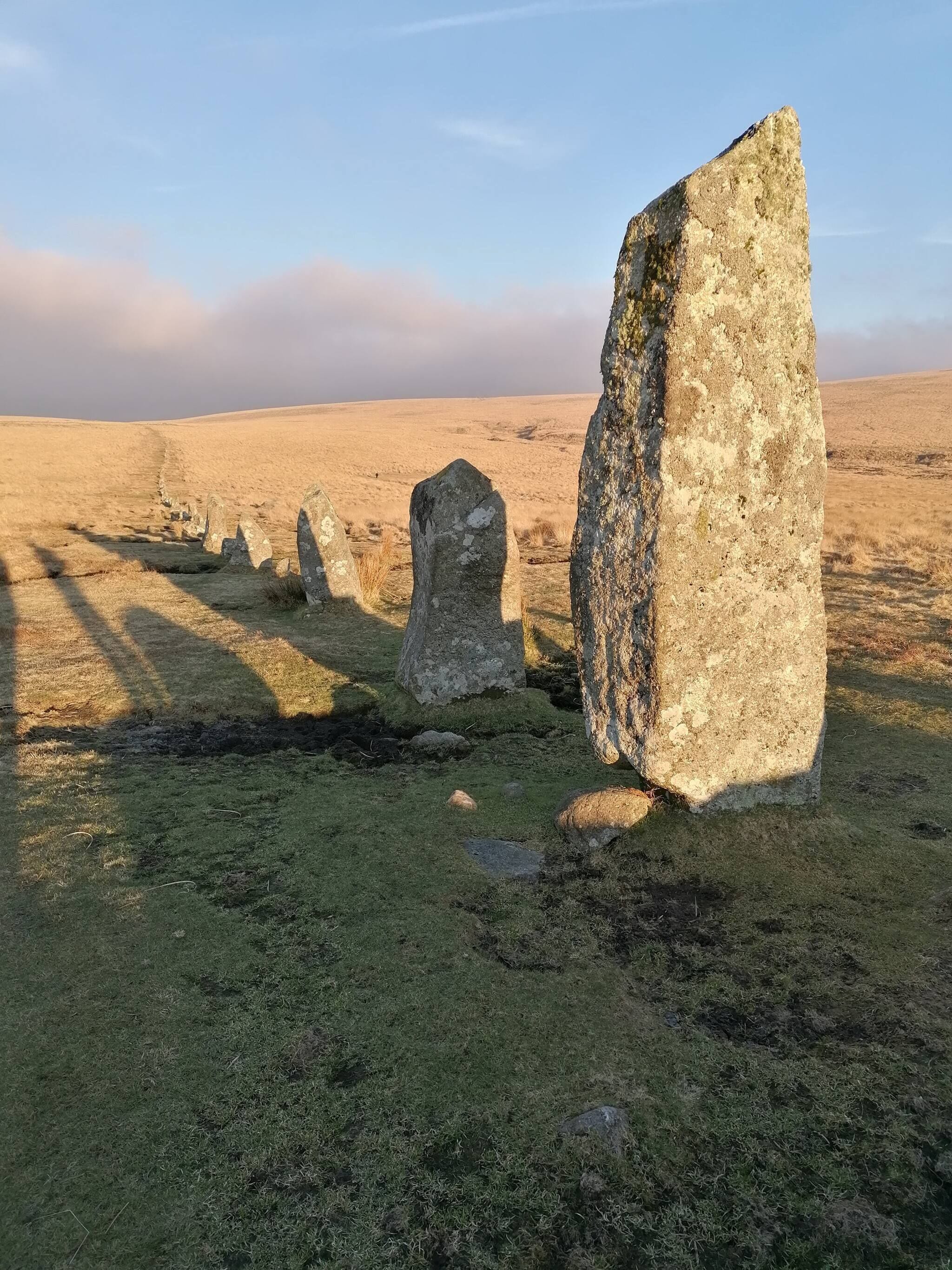 Un círculo de piedras verticales en un campo cubierto de hierba.