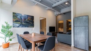 A modern hotel room with a dining area, a large painting, a potted plant, and a refrigerator. - Group-Friendly 3BR in Roma Norte (Ciudad de México)