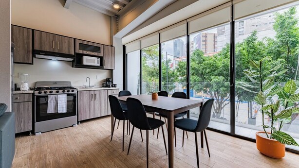 A modern kitchen with a dining area, large windows, and a view of the city. - Group-Friendly 3BR in Roma Norte (Ciudad de México)
