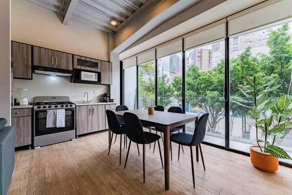 A modern kitchen with a dining area, large windows, and a view of the city. - Group-Friendly 3BR in Roma Norte (Ciudad de México)