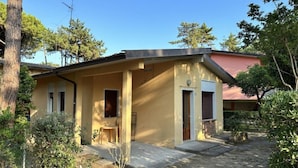 A two-story building with a covered porch, a small table, and a chair. - Functional Stay for Five Guests in Bibione (San Michele al Tagliamento)