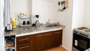 Uma cozinha compacta com bancada de granito, fogão embutido, pia e armários de madeira.