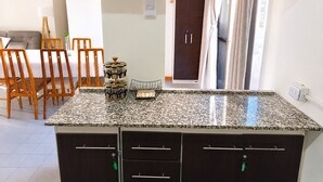 Uma cozinha com bancadas de granito, cadeiras de madeira, uma mesa de jantar e um guarda-roupa de madeira escura.