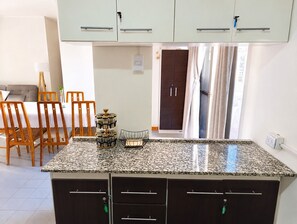 Eine Küche mit Granit Arbeitsplatten, Holzstühlen, einem Esstisch und einem dunklen Holzschrank.